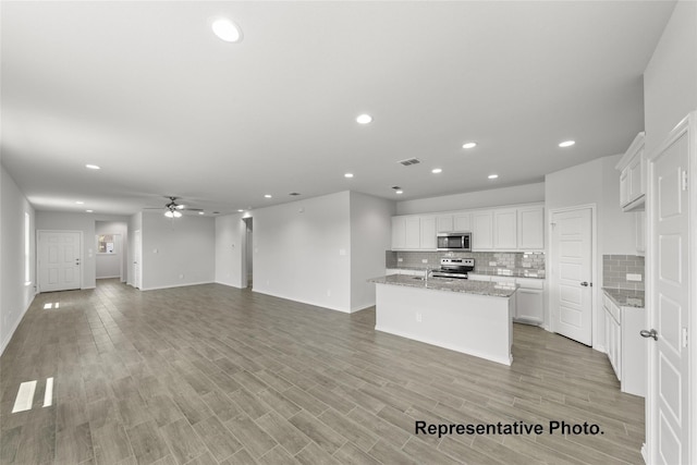 kitchen with visible vents, white cabinets, decorative backsplash, light wood-style flooring, and stainless steel appliances