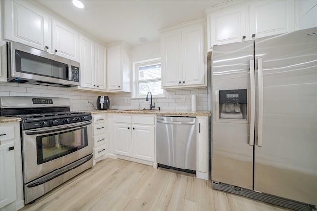 kitchen featuring backsplash, appliances with stainless steel finishes, white cabinets, and a sink