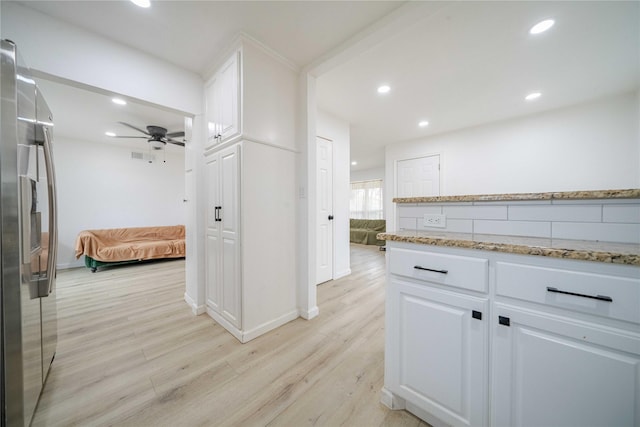 kitchen featuring stainless steel fridge with ice dispenser, light wood-type flooring, light stone countertops, and white cabinets