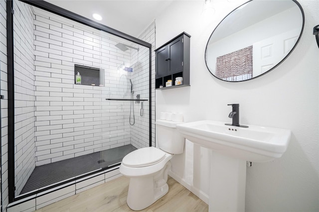 bathroom featuring a baseboard radiator, wood finished floors, toilet, and a shower stall