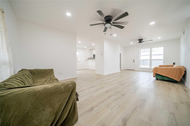 living area featuring a ceiling fan, recessed lighting, baseboards, and light wood finished floors