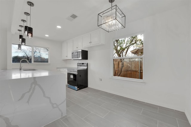 kitchen with light stone counters, decorative light fixtures, stainless steel appliances, white cabinets, and a sink