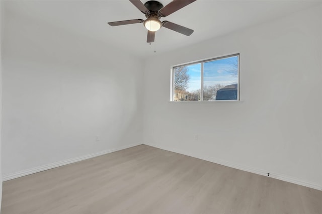 empty room featuring ceiling fan, light wood-style flooring, and baseboards