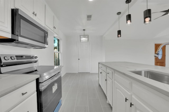 kitchen with light stone counters, white cabinetry, stainless steel appliances, and a sink