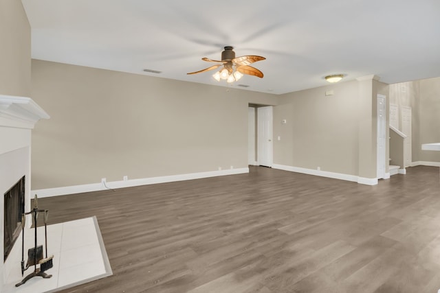 unfurnished living room featuring a ceiling fan, wood finished floors, visible vents, and a fireplace