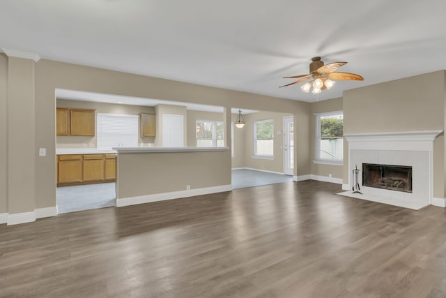 unfurnished living room with baseboards, a ceiling fan, wood finished floors, and a fireplace
