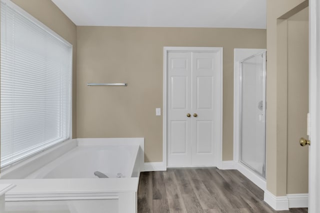 bathroom with a shower stall, a garden tub, and wood finished floors