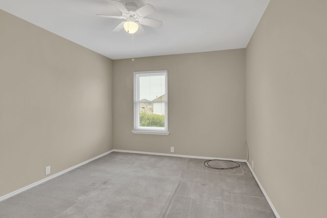 carpeted spare room featuring baseboards and ceiling fan