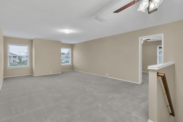 spare room featuring visible vents, light carpet, baseboards, and ceiling fan