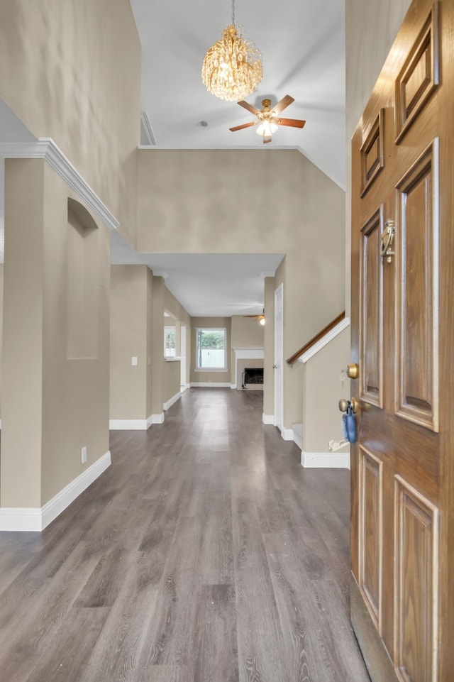 foyer featuring high vaulted ceiling, baseboards, dark wood-style flooring, and ceiling fan with notable chandelier