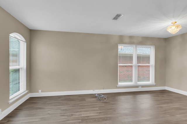unfurnished room featuring baseboards, wood finished floors, and visible vents
