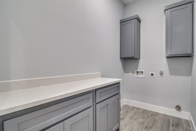 laundry room with hookup for a washing machine, wood finish floors, baseboards, cabinet space, and electric dryer hookup