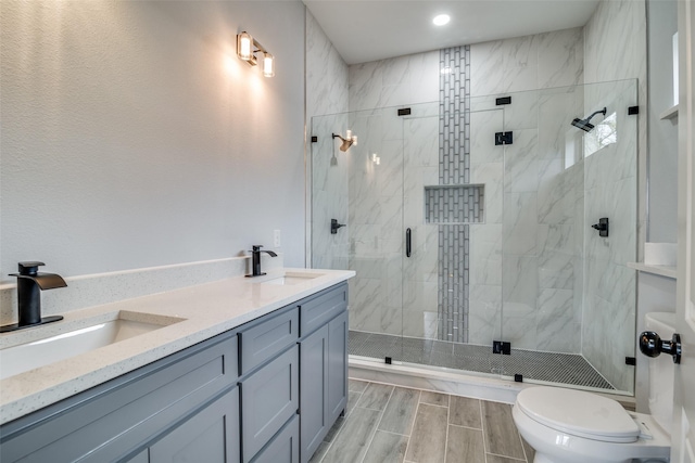 full bathroom featuring a shower stall, double vanity, a sink, and wood tiled floor