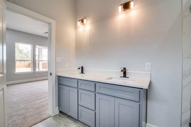 full bath with double vanity, a sink, and baseboards