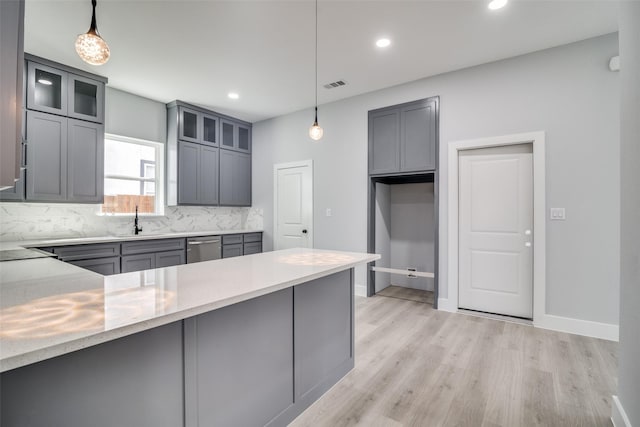 kitchen with glass insert cabinets, a sink, and decorative light fixtures