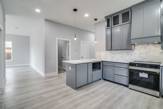 kitchen featuring decorative light fixtures, a peninsula, electric stove, light countertops, and glass insert cabinets