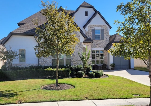 view of front facade featuring driveway, stone siding, an attached garage, and a front yard