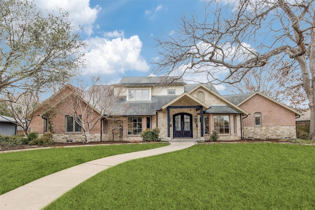 view of front of house with brick siding, french doors, and a front yard