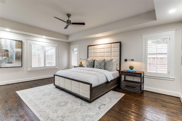 bedroom featuring baseboards, a raised ceiling, dark wood-type flooring, and recessed lighting