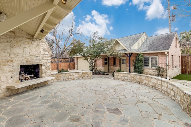 view of patio / terrace with driveway, an outdoor stone fireplace, an attached garage, and fence