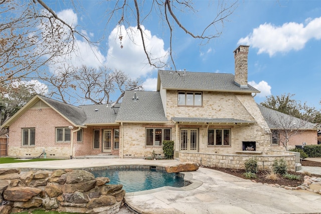 back of house featuring exterior fireplace, a chimney, a shingled roof, a patio area, and an outdoor pool