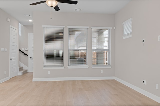 spare room featuring light wood-style flooring, visible vents, ceiling fan, and baseboards