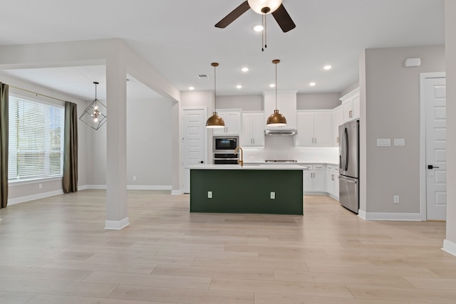 kitchen with ceiling fan, stainless steel appliances, light wood-type flooring, white cabinetry, and backsplash