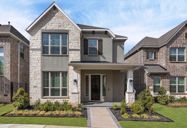 view of front of home featuring covered porch, stone siding, and a front yard