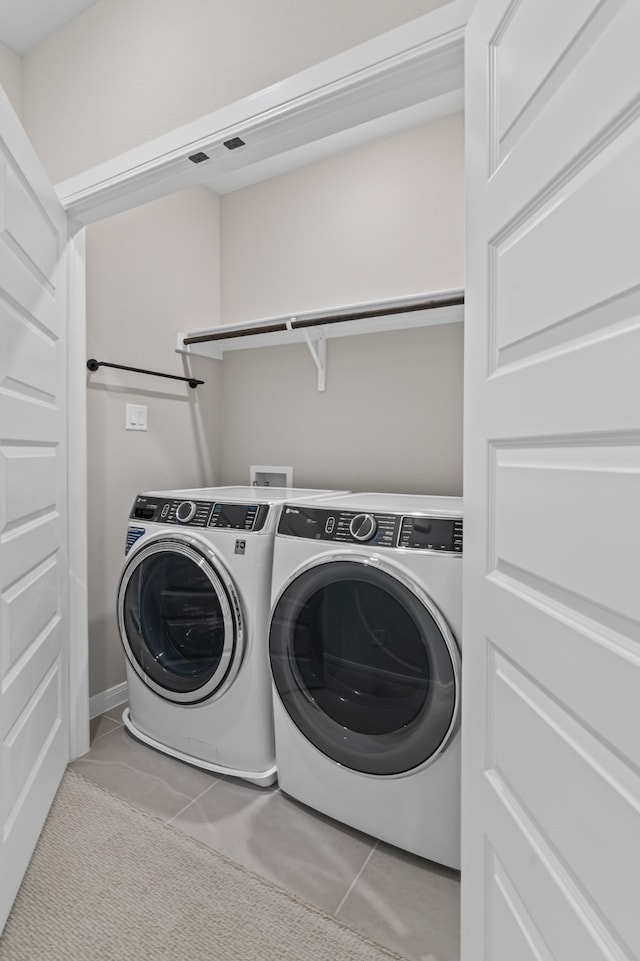 clothes washing area with laundry area, light tile patterned flooring, and washing machine and clothes dryer