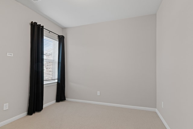 spare room featuring light colored carpet and baseboards