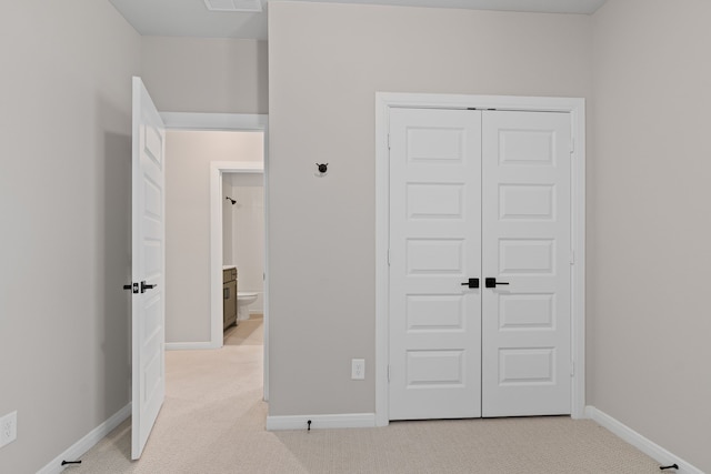 unfurnished bedroom featuring a closet, light carpet, visible vents, and baseboards