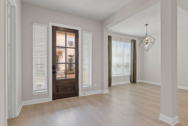 foyer with light wood-style floors, baseboards, and a notable chandelier