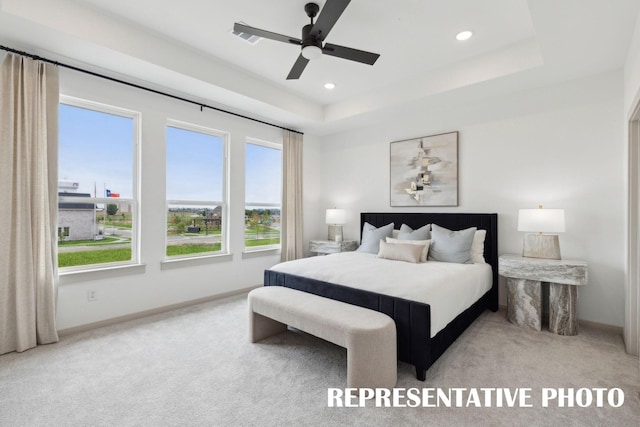 bedroom with recessed lighting, baseboards, a tray ceiling, and light colored carpet