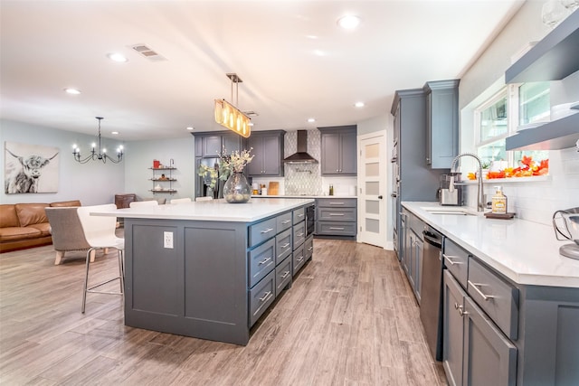 kitchen with wall chimney exhaust hood, hanging light fixtures, a kitchen island, and light countertops