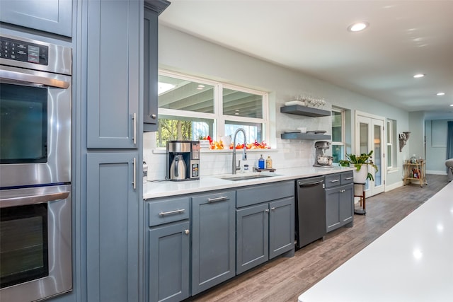 kitchen featuring stainless steel appliances, light countertops, a sink, and backsplash