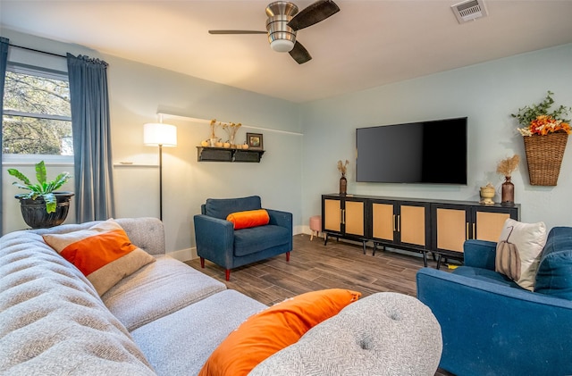 living room with baseboards, wood finished floors, visible vents, and a ceiling fan