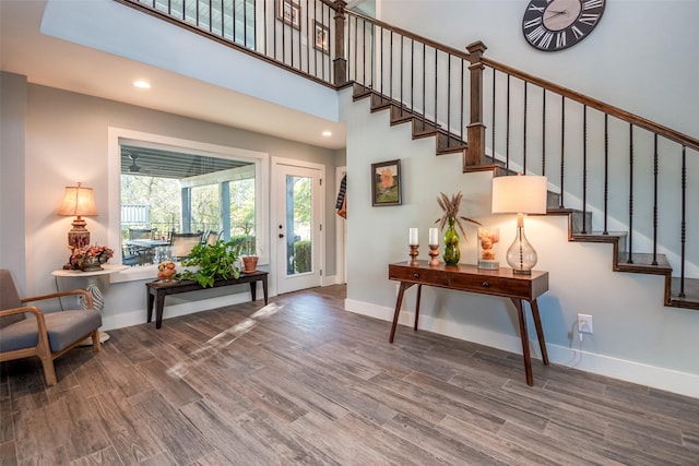 foyer entrance with a high ceiling, stairway, wood finished floors, and baseboards