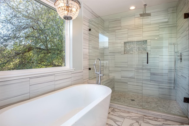 bathroom featuring a freestanding tub, a shower stall, marble finish floor, and an inviting chandelier