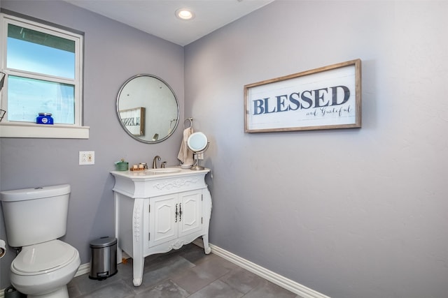 bathroom featuring toilet, vanity, and baseboards