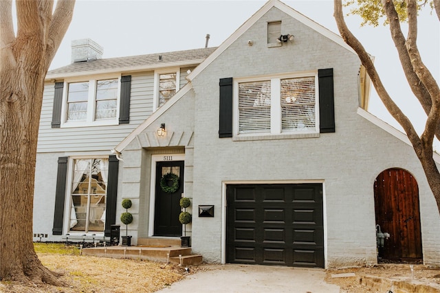 view of front facade featuring a garage, brick siding, and a chimney