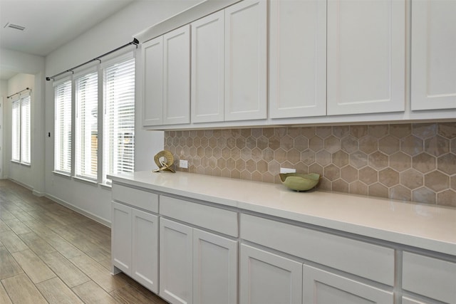 kitchen with visible vents, light countertops, backsplash, and wood finished floors