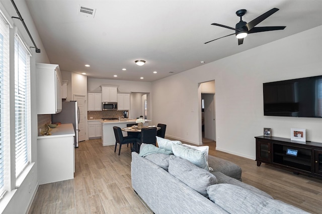 living area featuring light wood-type flooring, recessed lighting, ceiling fan, and plenty of natural light