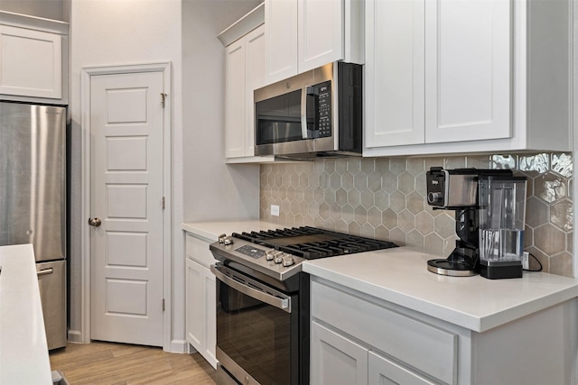 kitchen with stainless steel appliances, tasteful backsplash, light countertops, and light wood-style floors