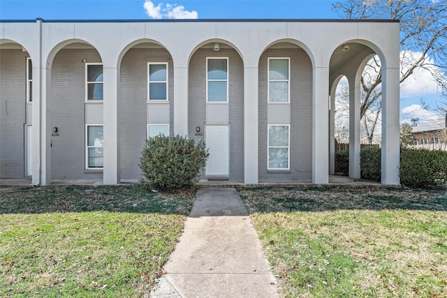 townhome / multi-family property featuring a front lawn and brick siding