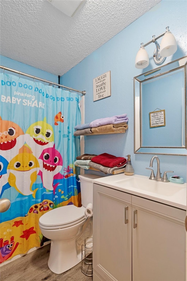 bathroom featuring toilet, vanity, a textured ceiling, wood finished floors, and a shower with curtain