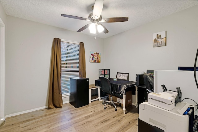 office with a textured ceiling, light wood-type flooring, a ceiling fan, and baseboards