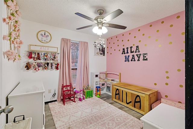 bedroom with ceiling fan, a textured ceiling, baseboards, and wood finished floors