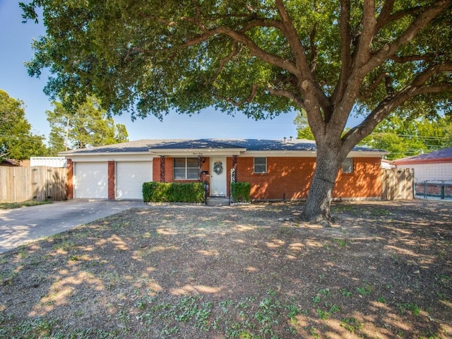 ranch-style house with a garage, brick siding, driveway, and fence