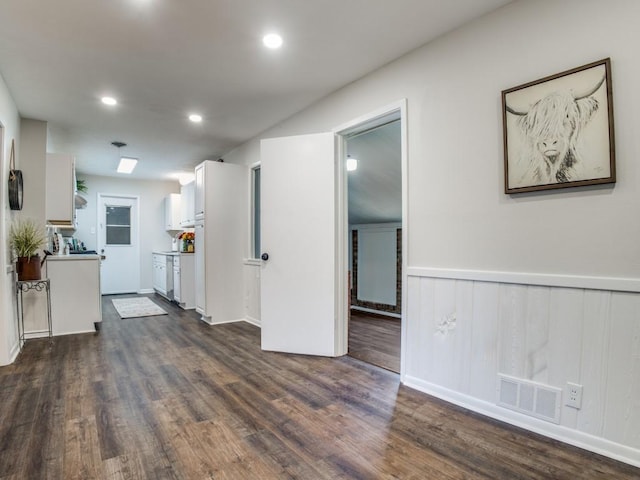 kitchen with a wainscoted wall, visible vents, white cabinets, light countertops, and dark wood finished floors