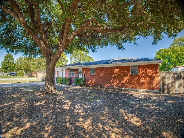 ranch-style house featuring brick siding and fence